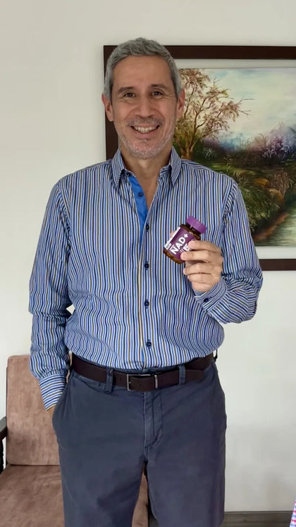 José Fernando de pie, sonriendo, con su frasco de MIMANAD