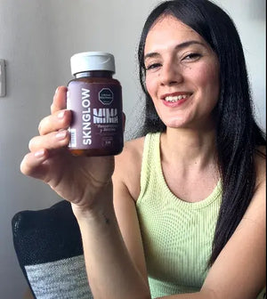 Clienta sonriendo levanta su frasco de Sknglow hacia la cámara