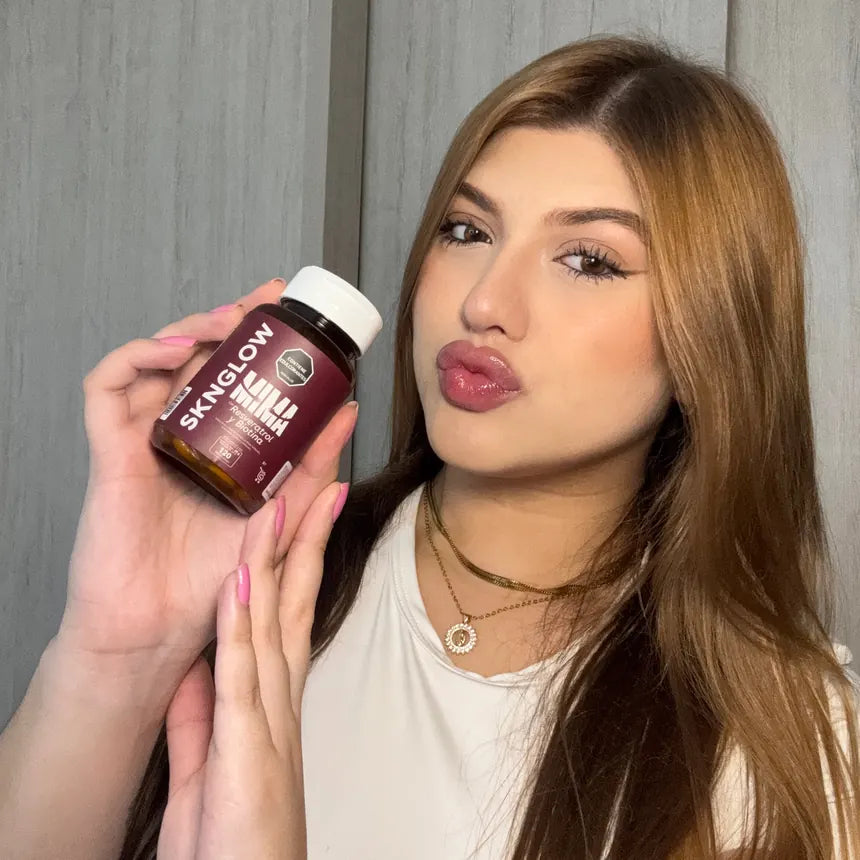 Clienta de MIMA con el cabello suelto sosteniendo su frasco de Sknglow