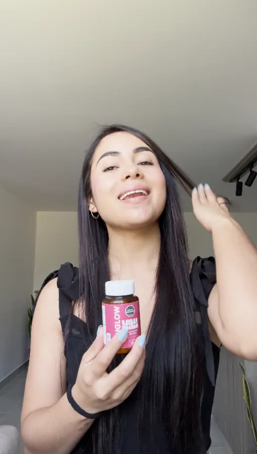 Clienta de MIMA con la mano en el cabello sosteniendo su frasco de Sknglow
